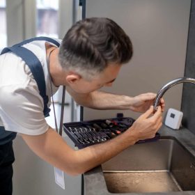 Engineer spinning a faucet aerator onto a spout pipe
